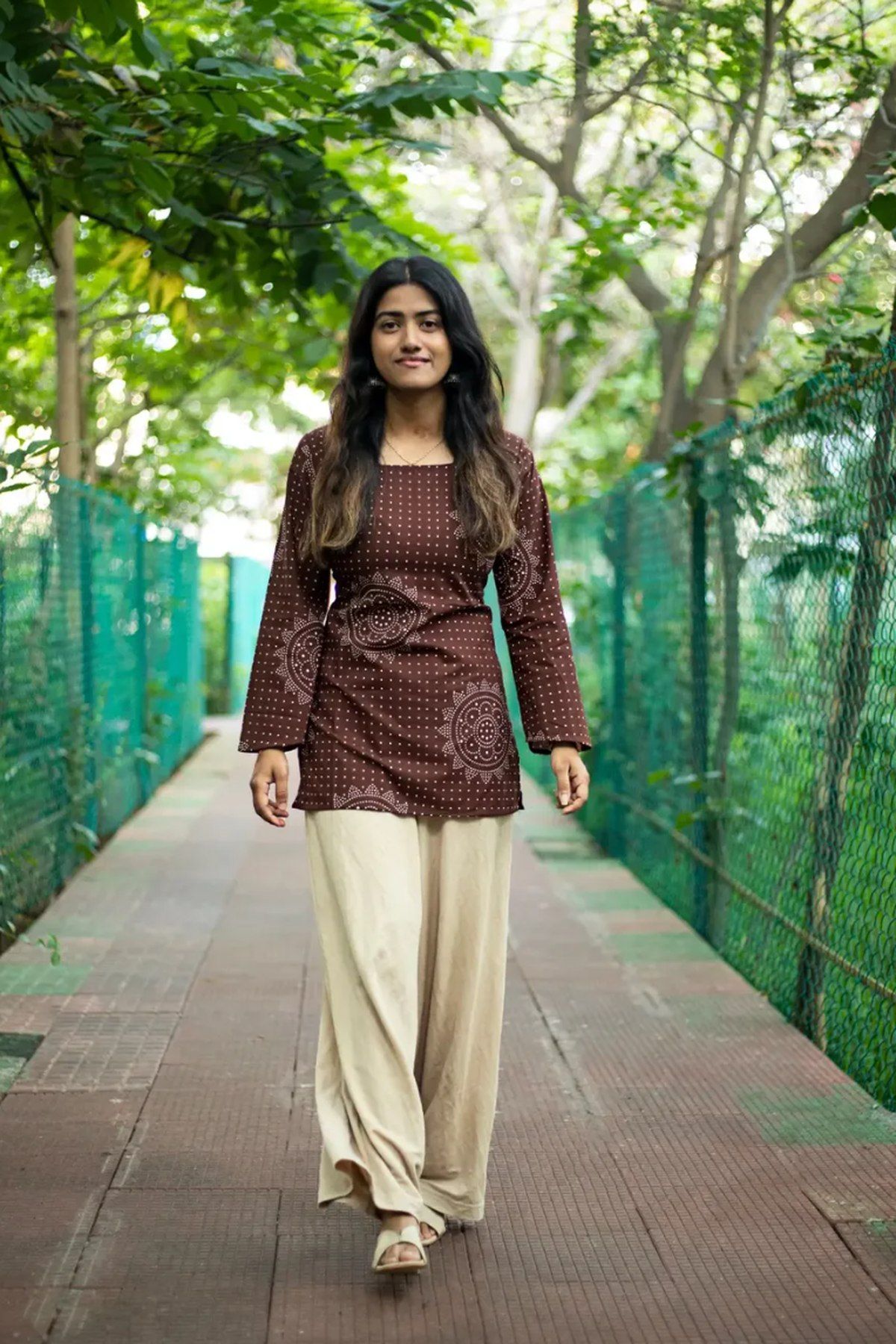 Full-length view of the cocoa bandhani top worn with cream palazzo
